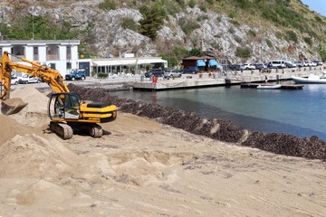 Fototapeta na wymiar Palinuro - Escavatore sulla spiaggia del porto