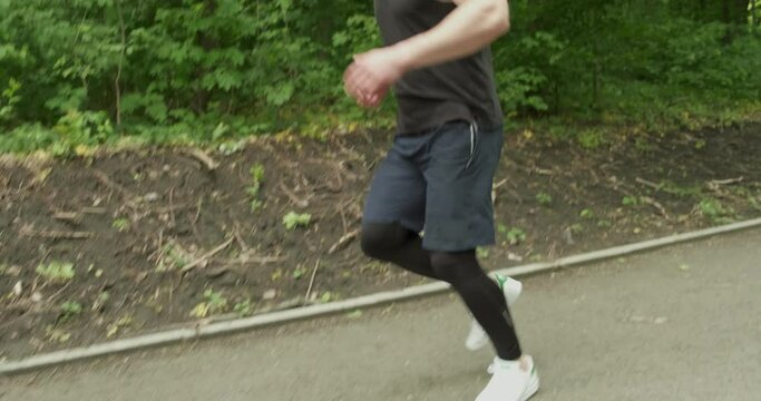 Young Male with Face Mask in Sportswear Running on the Road at Forest. Men doing intense run workout