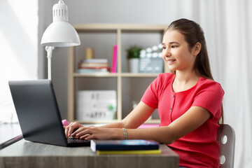 children, education and learning concept - happy smiling teenage student girl with laptop computer...