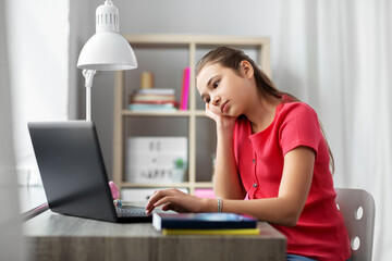 children, education and learning concept - bored teenage student girl with laptop computer at home