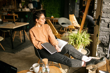 young stylish girl girl drinks coffee. Girl blogger with a cup of coffee in cafe with magazine 