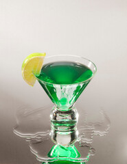 Green martini cocktail with lemon dice on a black glass background  