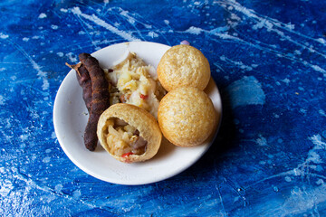 Golgappa or Panipuri with Tamarind and Spicy Potato Stuff in a Plate Isolated on Beautiful Bluish Background, Also Known as Phuchka, Paani Patashi,, Gup Chup etc