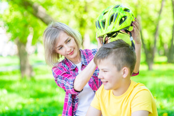 Mother put on helmet to her son for a safe ride on a bike