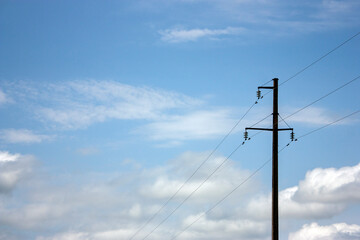 Pylon of high-voltage power lines on a background of the sky in the clouds. Metal support of high-voltage line in the form of a concrete pillar with garlands of insulators with wires.