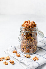 Homemade oatmeal granola in open glass jar on white background.