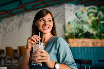 Close-up portrait of a positive woman drinking latte at the cafe.