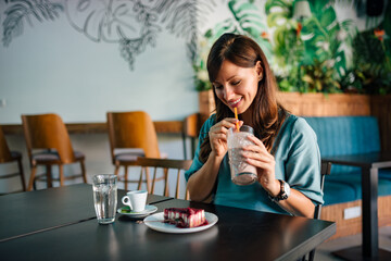 Cheerful brunette having delicious cake dessert and drink, portrait.