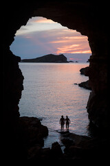 Silhouette of two women in a cove in Ibiza with the sunset in the background. Friendship and human relations