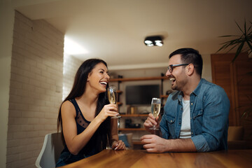 Loving couple having fun at home, drinking glass of champagne, portrait.