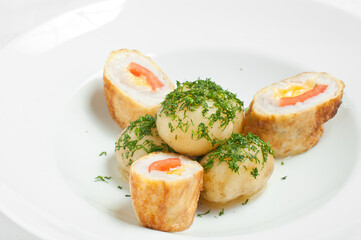 Young potatoes with meatballs and herbs on a white plate.