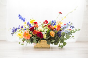 Horizontal shot of a bouquet full of different colored flowers in a square basket