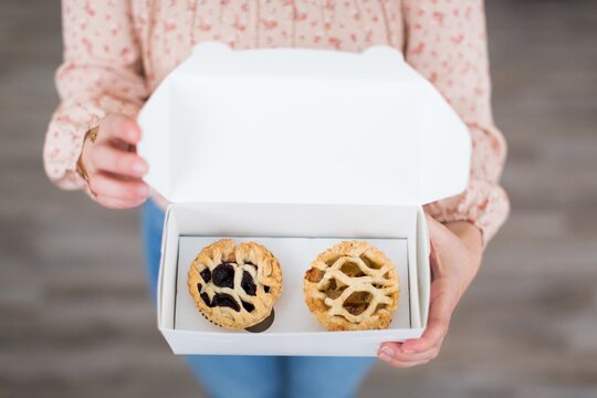 Overhead Shot Of A Female Holding A White Box Containing Two Small Pastries