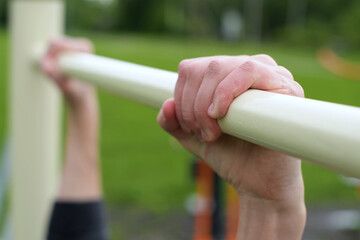 guy's hands on the horizontal bar, selective focus