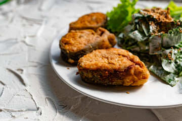 Colorful delicious dish with a salad of sorrel and sour cream, topped with fried sesame seeds, next to fried steaks of red fish pink salmon in breadcrumbs