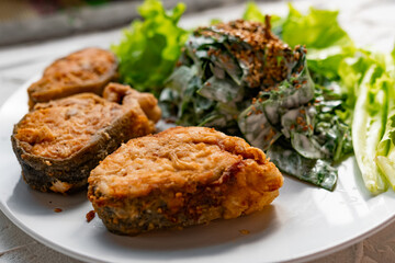 Colorful delicious dish with a salad of sorrel and sour cream, topped with fried sesame seeds, next to fried steaks of red fish pink salmon in breadcrumbs