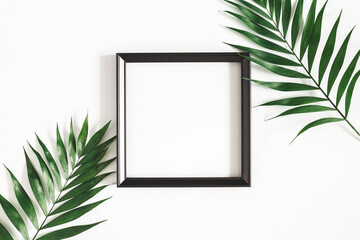 Summer composition. Tropical palm leaves, white photo frame on white background. Summer, nature...