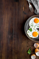 Fried eggs on frying pan on wooden desk top-down copy space