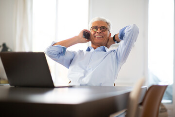 relaxed business man sitting at table talking on phone
