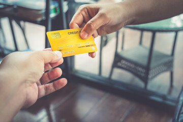 Closeup of businesspeople giving paying for goods with yellow credit card at the store. Making debit money and shopping on banking in cafe. Woman employee taking payment from the customer. 