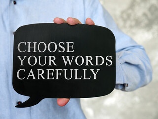 Hand holds a black tablet with the inscription Choose Your Words Carefully. © Vitalii Vodolazskyi