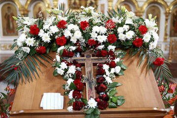 Fototapeta na wymiar Flowers around wooden cross in Church