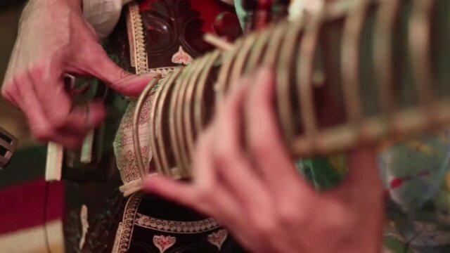 Close up of mans hands playing an Indian instrument called a sitar
