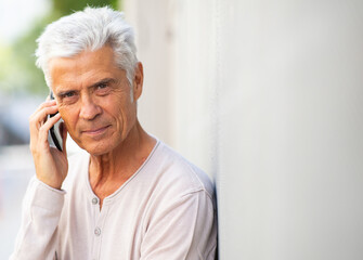 Close up handsome older man talking with cellphone outside