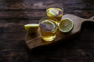 Cold kombucha with lemon in glasses on wooden background. Summer fermented raw tea