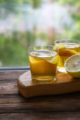 Cold kombucha with lemon in glasses on wooden background. Summer fermented raw tea