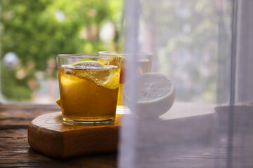 Cold kombucha with lemon in glasses on wooden background with copy space. Summer fermented raw tea
