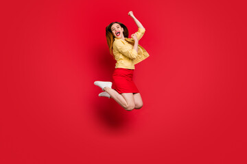 Full length profile photo of funky lady good mood jump high up cheerleader support sports team wear casual yellow blazer jacket short skirt white sneakers isolated red color background