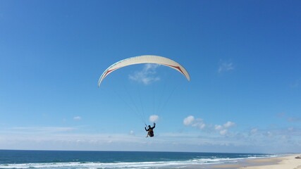 Paraglider fliegt über einen Strand am atlantische Ozean