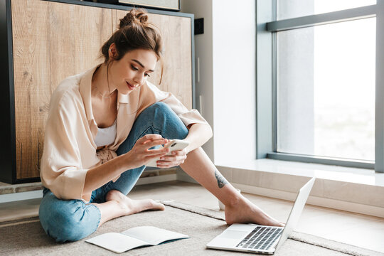 Image of woman using smartphone and laptop while sitting on floor - Image of lifestyle, A person usi