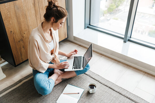 Image of woman working with laptop while sitting on floor