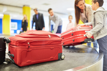 Familie und Reisende am Gepäckband holen Koffer ab