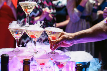 Champagne slide. Pyramid or fountain made of champagne glasses with cherry and steam from dry ice