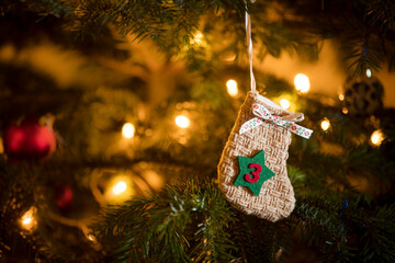 Traditional Advent Calendar Stocking with the date of the third of December hanging on a traditional christmas tree.