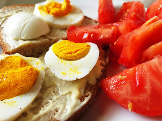 A light Breakfast of wholegrain bread, boiled eggs and tomatoes.