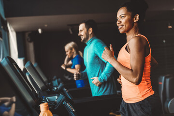 Fototapeta na wymiar Young people running on a treadmill in modern gym