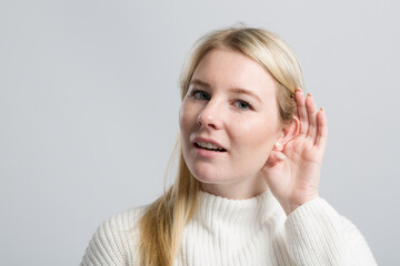 Young woman with hand at her ear tries to listen better