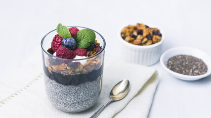 Chia pudding dessert with raspberry jam and granola, mint, blueberry, raspberry on the top