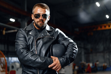 Portrait of bearded man motocyclist in dark sunglasses on dark background