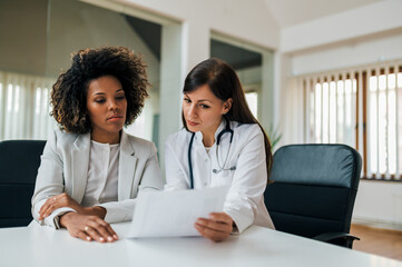 People, healthcare and medicine concept. Female doctor explaining test results to her patient, front view.