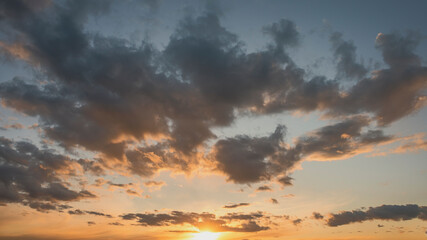 sun sets behind the clouds in the blue evening sky as a natural background