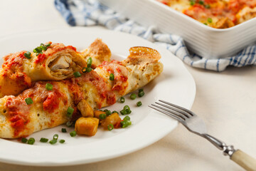 Baked pancakes with chicken in tomato sauce.