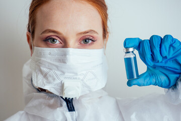 virologist woman in chemical protection mask ,glasses and gloves holding potential vaccine at the lab