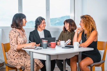 Session young entrepreneurs in the office, a young man of Latin ethnicity and three young Caucasian women sitting at a table in the office one summer morning