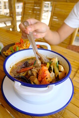 Boiled pork ribs in a white cup on a piece of fabric on a wooden table. ,Hot and spicy pork ribs soup