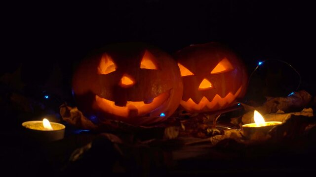 Halloween, two pumpkins with a scary glowing face inside, candles burn and the wind blows.